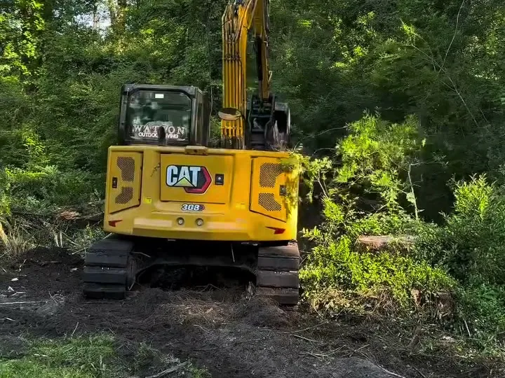 CAT 308 working through green brush