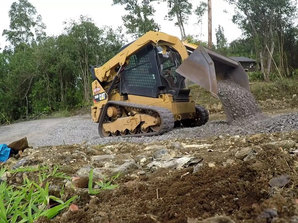 Gravel driveway install with a compact track loader dumping crushed stone on a new drive